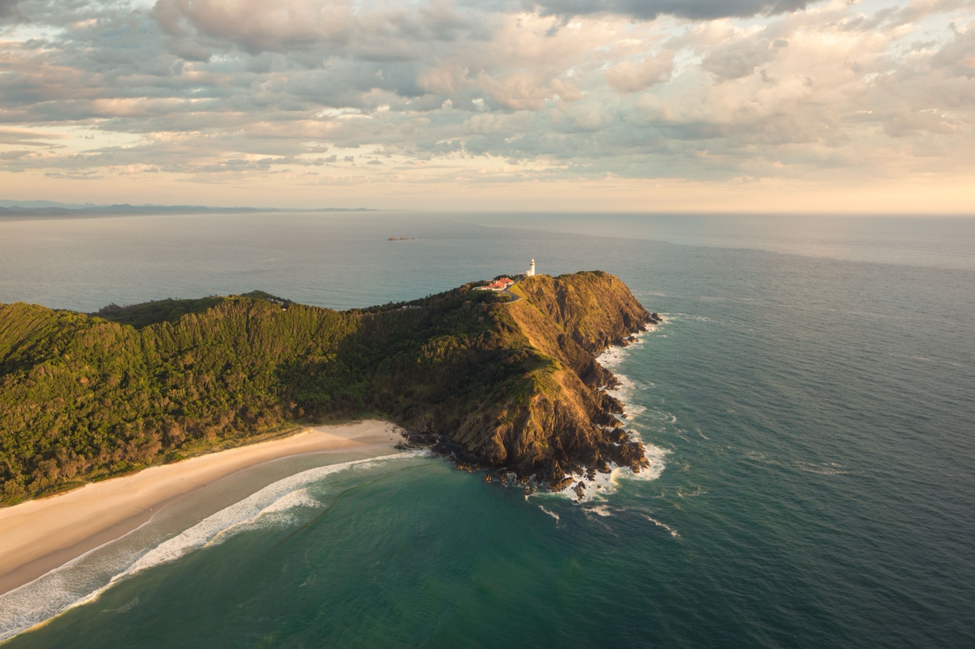 Cape Byron lighthouse on a green headland above turquoise ocean