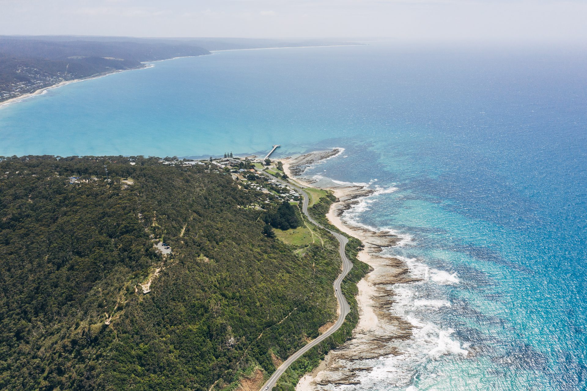 The Great Ocean Road winding along a green coastal hillside above the ocean
